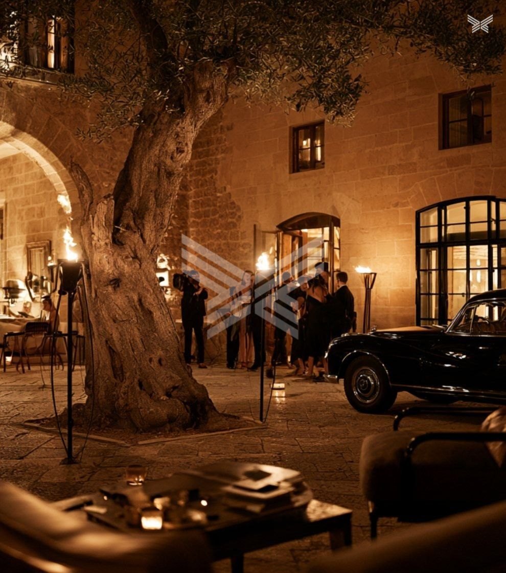 Torch-lit palacio courtyard with an olive tree and leather lounge chairs