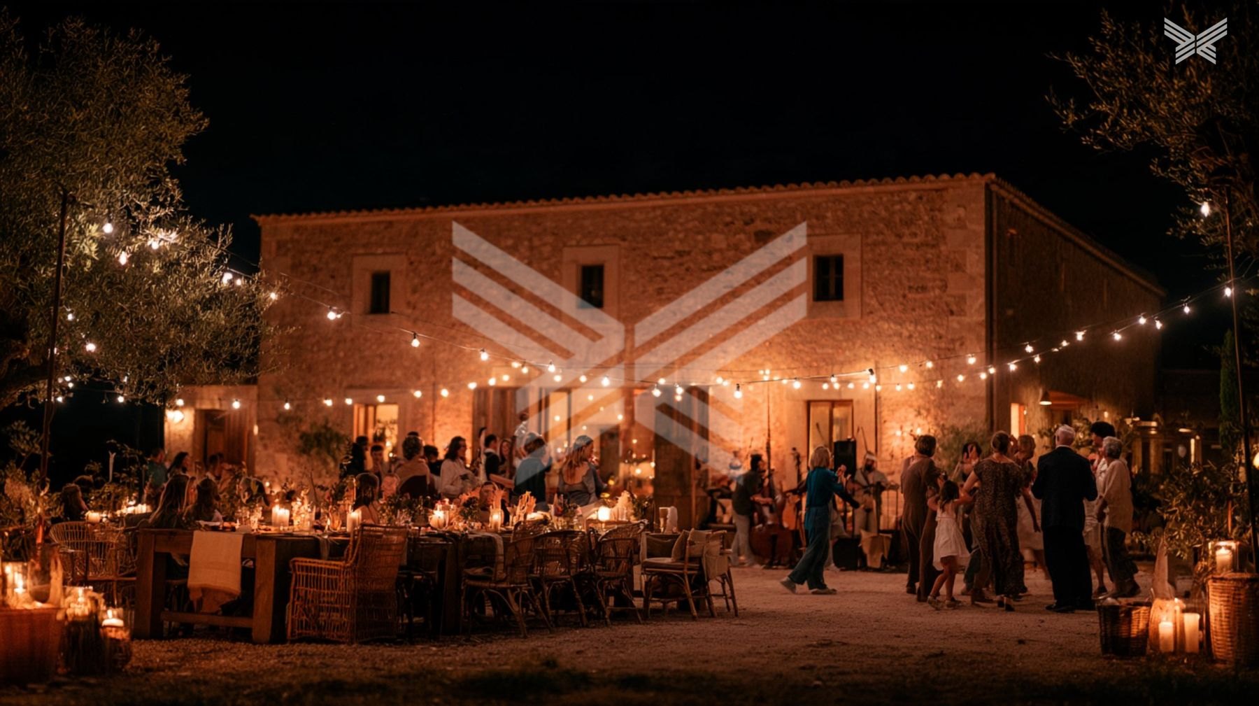 Community feast at a stone barn under string lights